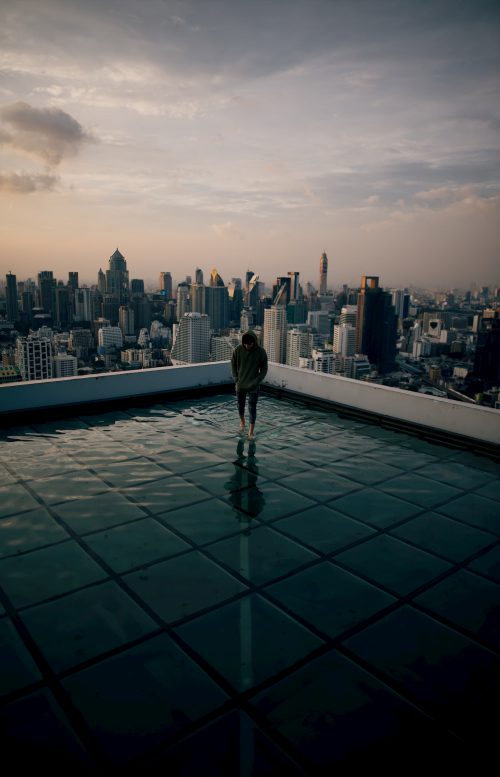 Man standing on roof of building surrounded by buildings